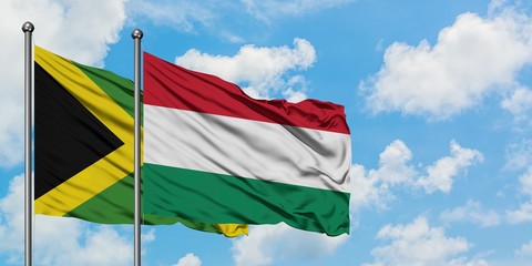 Jamaica and Hungary flag waving in the wind against white cloudy blue sky together. Diplomacy concept, international relations.