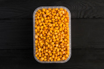 Frozen sea buckthorn in the plastic box in the center of  the black wooden background.Top view. Copy space.