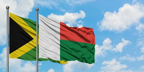 Jamaica and Madagascar flag waving in the wind against white cloudy blue sky together. Diplomacy concept, international relations.
