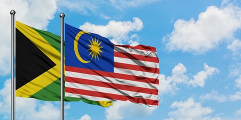 Jamaica and Malaysia flag waving in the wind against white cloudy blue sky together. Diplomacy concept, international relations.