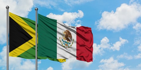 Jamaica and Mexico flag waving in the wind against white cloudy blue sky together. Diplomacy concept, international relations.