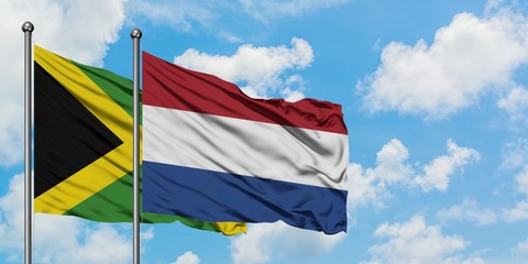 Jamaica and Netherlands flag waving in the wind against white cloudy blue sky together. Diplomacy concept, international relations.