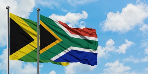 Jamaica and South Africa flag waving in the wind against white cloudy blue sky together. Diplomacy concept, international relations.