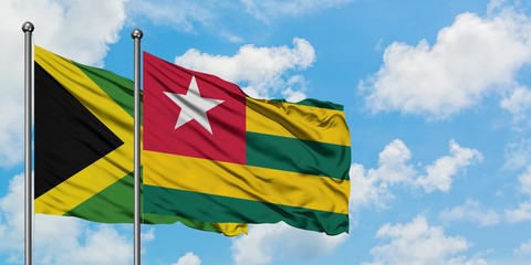 Jamaica and Togo flag waving in the wind against white cloudy blue sky together. Diplomacy concept, international relations.