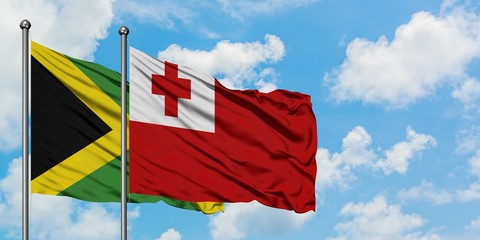Jamaica and Tonga flag waving in the wind against white cloudy blue sky together. Diplomacy...