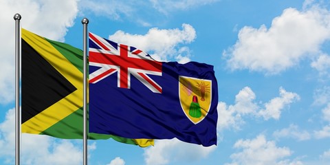 Jamaica and Turks And Caicos Islands flag waving in the wind against white cloudy blue sky together. Diplomacy concept, international relations.