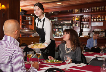 Young waitress serving couple