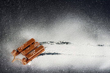 wooden sled on white snow on a black background, top view