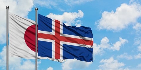 Japan and Iceland flag waving in the wind against white cloudy blue sky together. Diplomacy...