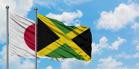 Japan and Jamaica flag waving in the wind against white cloudy blue sky together. Diplomacy concept, international relations.