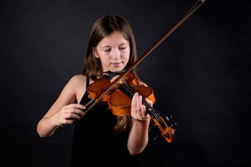 Young professional violinist playing and exercising on black background