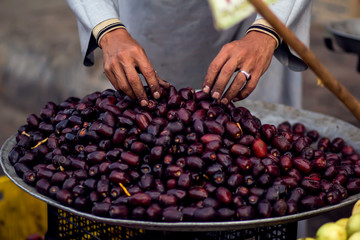 A seller man touches fresh dates on the plate at the bazaar