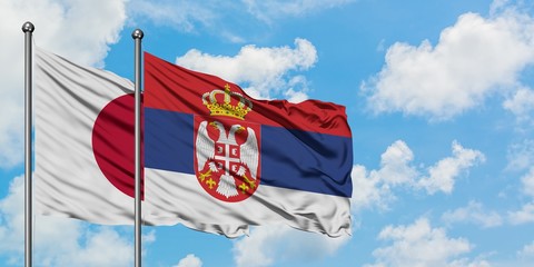 Japan and Serbia flag waving in the wind against white cloudy blue sky together. Diplomacy concept, international relations.