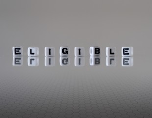 The concept of eligible represented by black and white plastic letter cubes