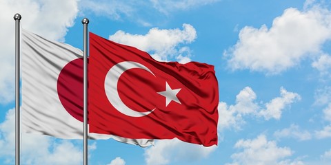 Japan and Turkey flag waving in the wind against white cloudy blue sky together. Diplomacy concept, international relations.