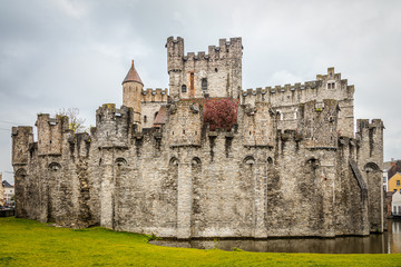 Fototapeta na wymiar Fortified walls and towers of Gravensteen medieval castle with moat in the foreground, Ghent East Flanders, Belgium
