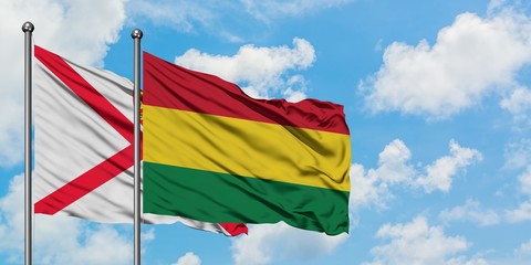 Jersey and Bolivia flag waving in the wind against white cloudy blue sky together. Diplomacy concept, international relations.