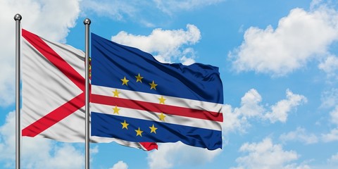 Jersey and Cape Verde flag waving in the wind against white cloudy blue sky together. Diplomacy concept, international relations.