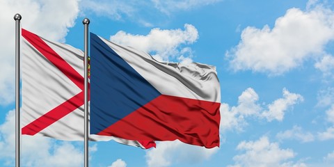 Jersey and Czech Republic flag waving in the wind against white cloudy blue sky together. Diplomacy...