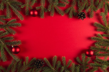 Christmas tree branches and pine cones on a red background, Christmas concept, greeting card copy space.