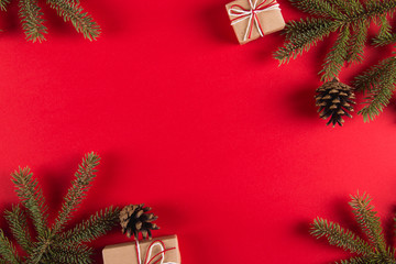 Christmas tree branches, gifts and pine cones on a red background, Christmas concept, greeting card copy space.