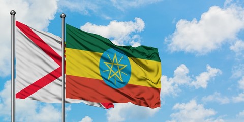 Jersey and Ethiopia flag waving in the wind against white cloudy blue sky together. Diplomacy concept, international relations.