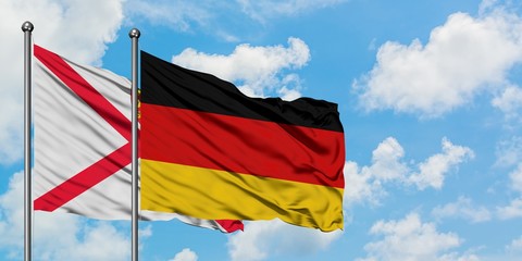 Jersey and Germany flag waving in the wind against white cloudy blue sky together. Diplomacy concept, international relations.