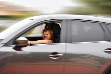 Naklejka premium Smiling asian woman driving a fast car