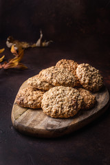 Homemade oatmeal cookies on a wooden cutting board. Dark background. Rustic style