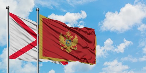 Jersey and Montenegro flag waving in the wind against white cloudy blue sky together. Diplomacy concept, international relations.