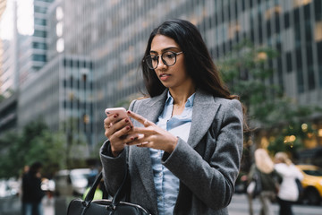 Fototapeta premium Modern young female with smartphone in hands outside