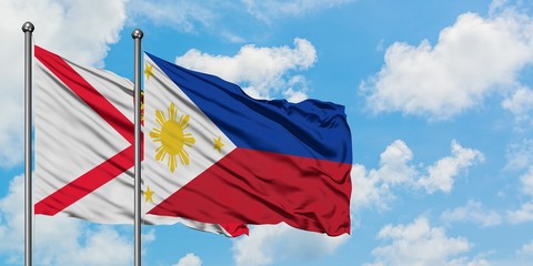 Jersey and Philippines flag waving in the wind against white cloudy blue sky together. Diplomacy concept, international relations.