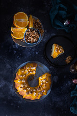 Bundt cake, orange cake with walnuts and yellow sugar icing with turmeric spice. Dark background. View from above. With a cut piece