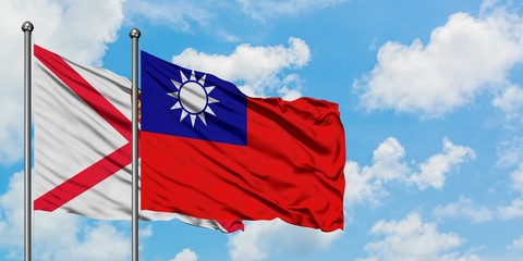 Jersey and Taiwan flag waving in the wind against white cloudy blue sky together. Diplomacy concept, international relations.