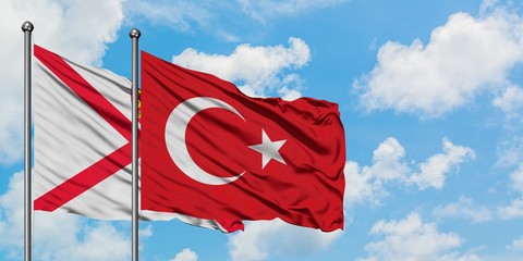 Jersey and Turkey flag waving in the wind against white cloudy blue sky together. Diplomacy concept, international relations.