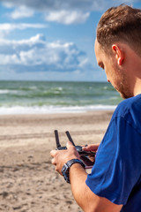 Man flying his drone by using a remote controller on the beach