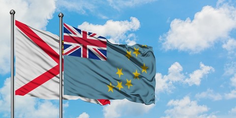 Jersey and Tuvalu flag waving in the wind against white cloudy blue sky together. Diplomacy...