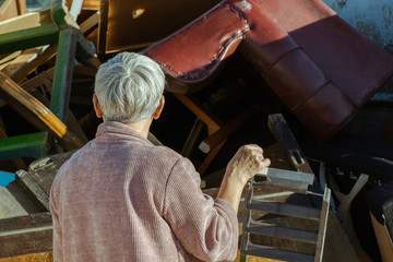 senior woman looking at a container full of old furniture