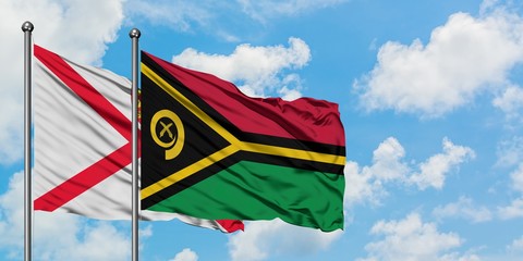 Jersey and Vanuatu flag waving in the wind against white cloudy blue sky together. Diplomacy...