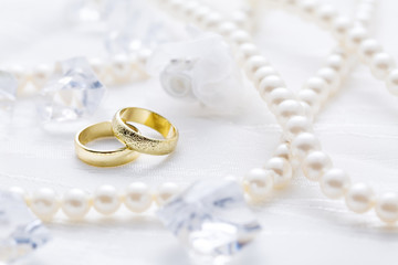 Two golden rings with pearl necklace and on white background