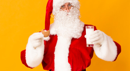 Obraz na płótnie Canvas Santa eating cookie and drinking milk on orange background