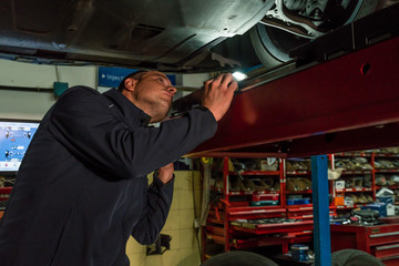 Fototapeta na wymiar Auto mechanic working in mechanical workshop. Checking brakes and suspensions
