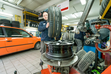 Auto mechanic working in mechanical workshop. Tire replacement.