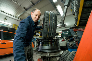 Auto mechanic working in mechanical workshop. Tire replacement.