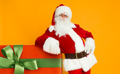 Santa Claus posing with Christmas gift in big red box