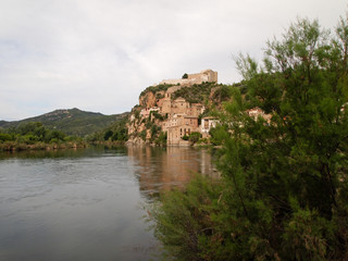 Fototapeta na wymiar View from the river to the ancient walls of the fortress Miravet Templar order, on the high Bank of the river Ebro.