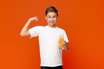 Fototapeta na wymiar Confident teenager with orange juice showing strong biceps