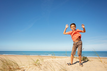 Cute boy jump on the sand dune at sea beach