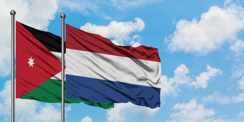 Jordan and Netherlands flag waving in the wind against white cloudy blue sky together. Diplomacy concept, international relations.