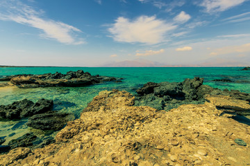 tranquillity and silence , abandoned beach with azure water, rocks on coast, beautiful turquoise sea with mild surf, deep blue sky with clouds and mountains on background, Mediterranean landscape